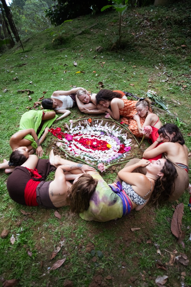 Women gathered in circle around a flower mandala