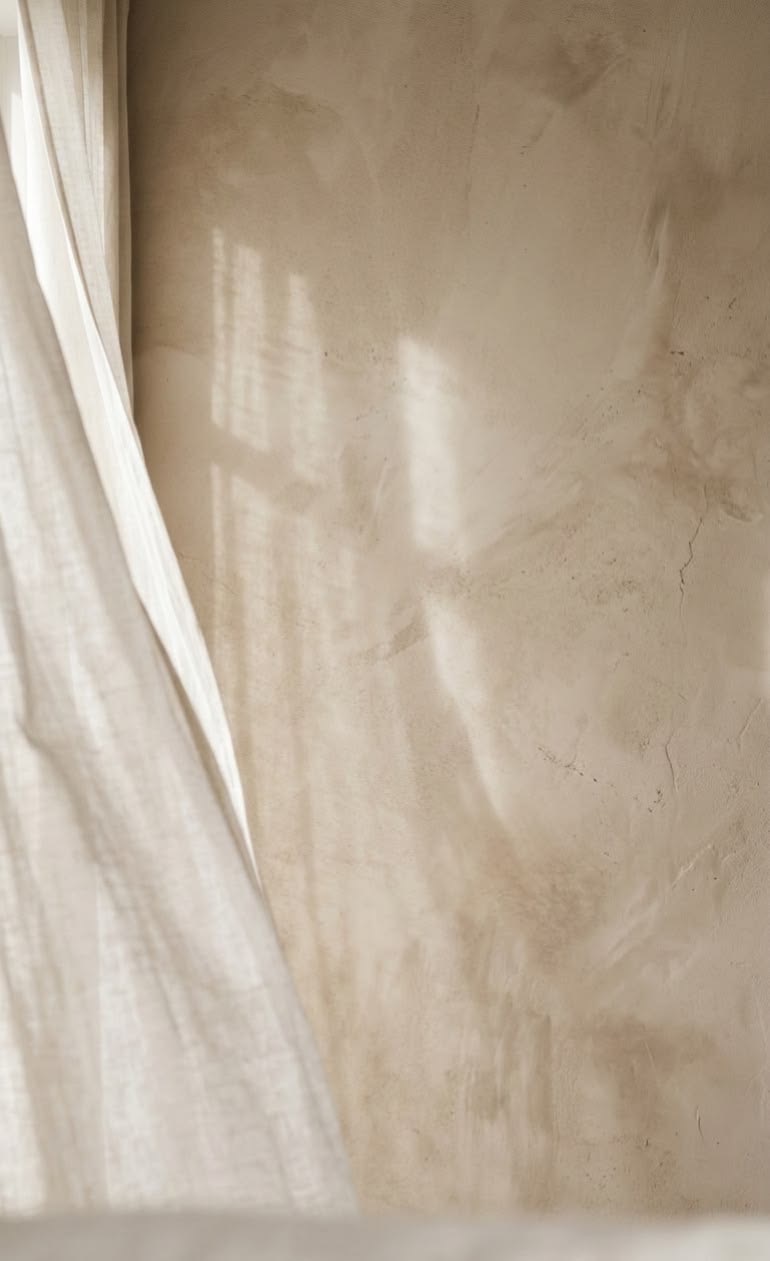 Soft light through a curtain onto a plaster wall