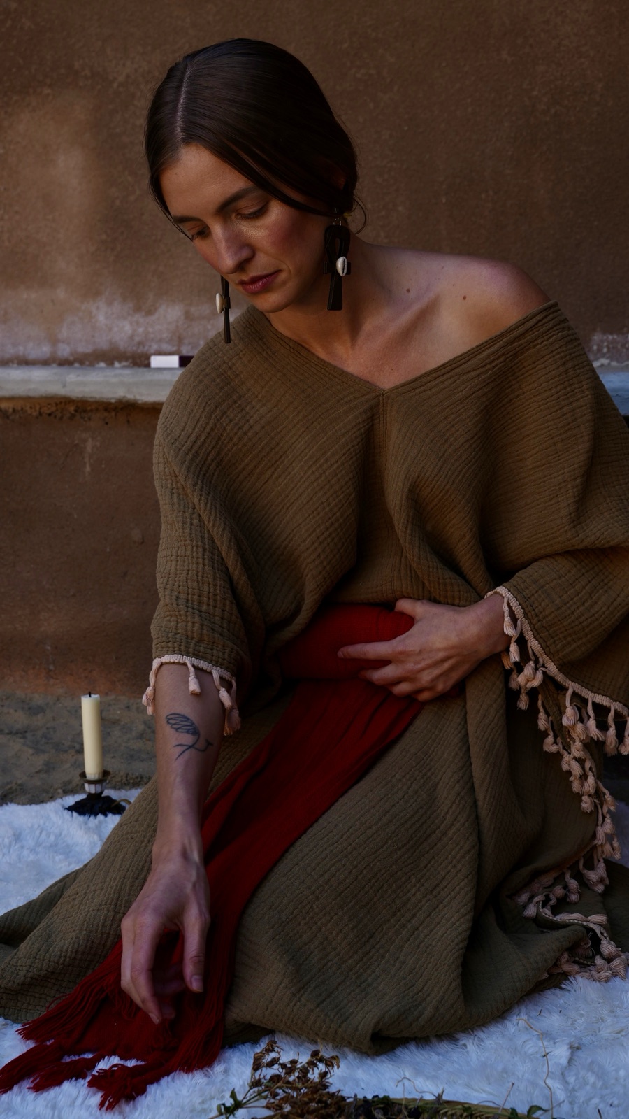 Bliss with a hand resting on her belly over a red cloth